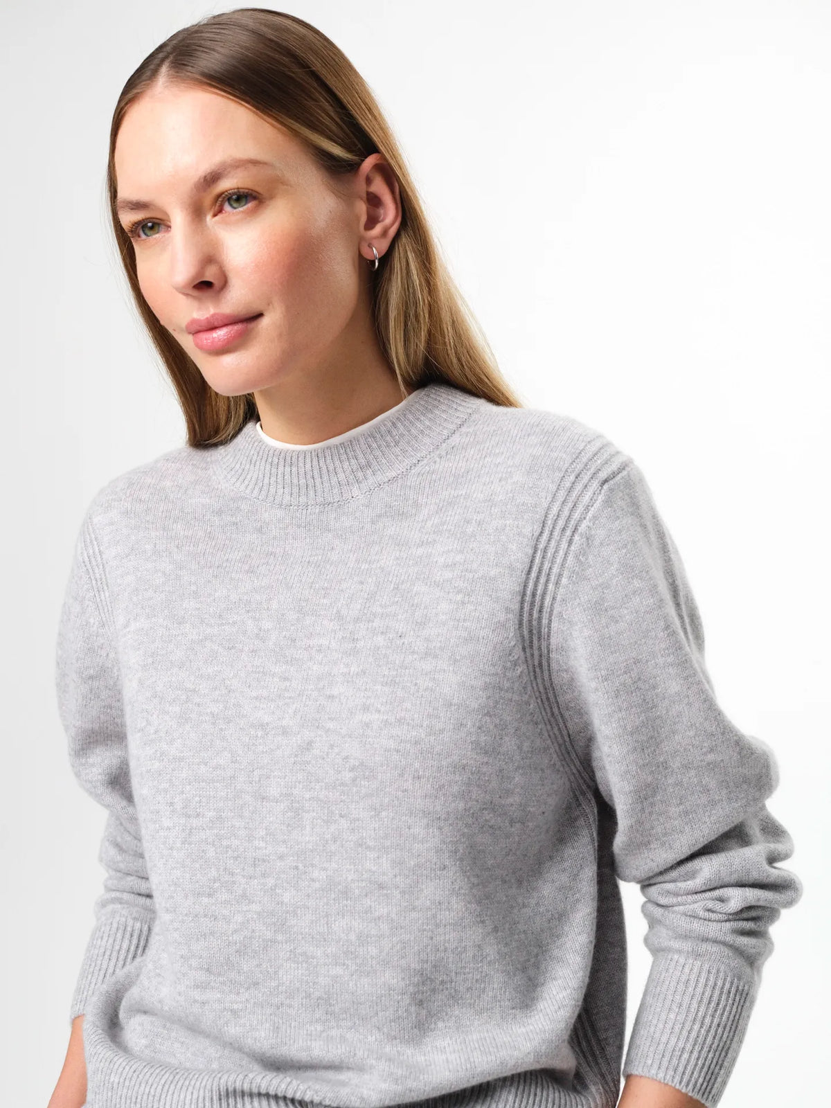 Model wearing the Alma Sweater in husky grey, a soft wool-cashmere crewneck with long sleeves and a clean, regular fit.