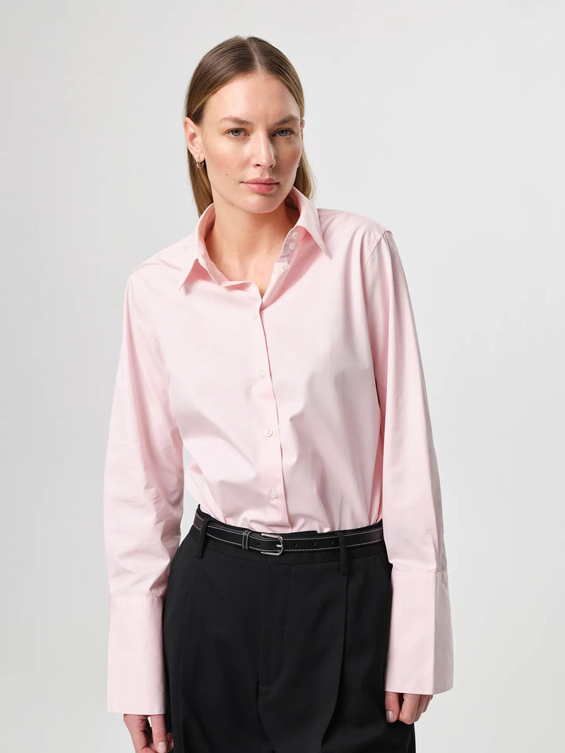 Julie Josephine Julie Shirt Peony Pink: iconic bestselling cotton twill shirt in peony pink made from crisp 100% cotton, tailored with a fitted shoulder and clean straight body for a polished silhouette, finished with elongated statement cuffs and a modern curved hem, designed to wear untucked or layered under a favorite knit with the cuffs showing, crafted in Portugal as a timeless wardrobe staple made to be worn, loved, and kept for years.