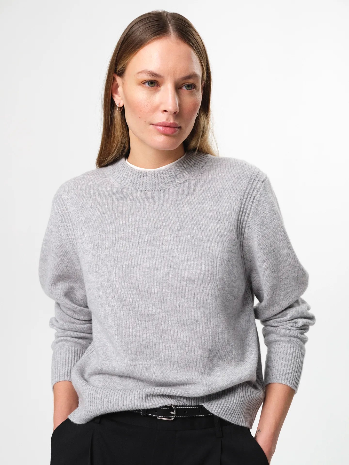 Model wearing the Alma Sweater in husky grey, a soft wool-cashmere crewneck with long sleeves and a clean, regular fit.