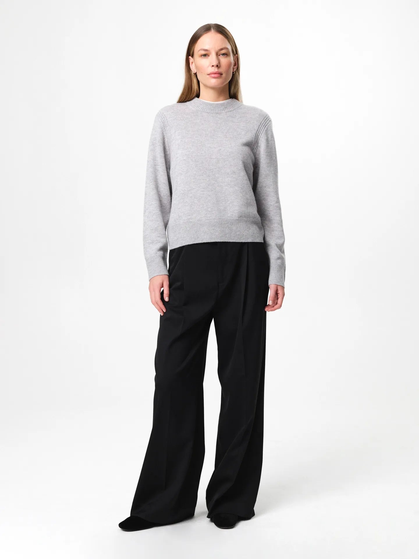 Model wearing the Alma Sweater in husky grey, a soft wool-cashmere crewneck with long sleeves and a clean, regular fit.