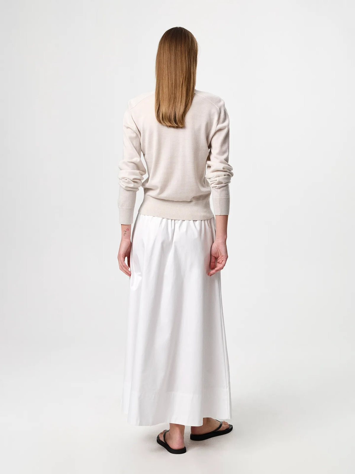Julie Josephine Hanne Sweater Oatmeal: product photo of a clean, timeless round neck sweater in an oatmeal shade, knitted in 100% fine merino wool with a lightweight knit and a soft, luxurious feel, designed to be worn on its own or layered over a t shirt for an effortless everyday look, note that it fits small so sizing up gives a more relaxed fit.