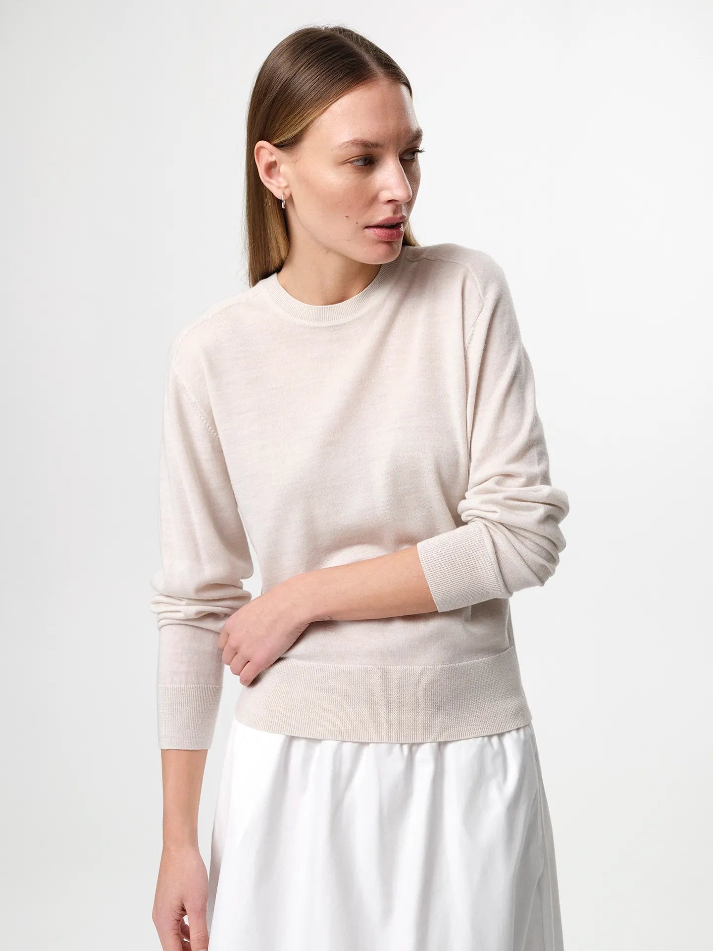 Julie Josephine Hanne Sweater Oatmeal: product photo of a clean, timeless round neck sweater in an oatmeal shade, knitted in 100% fine merino wool with a lightweight knit and a soft, luxurious feel, designed to be worn on its own or layered over a t shirt for an effortless everyday look, note that it fits small so sizing up gives a more relaxed fit.