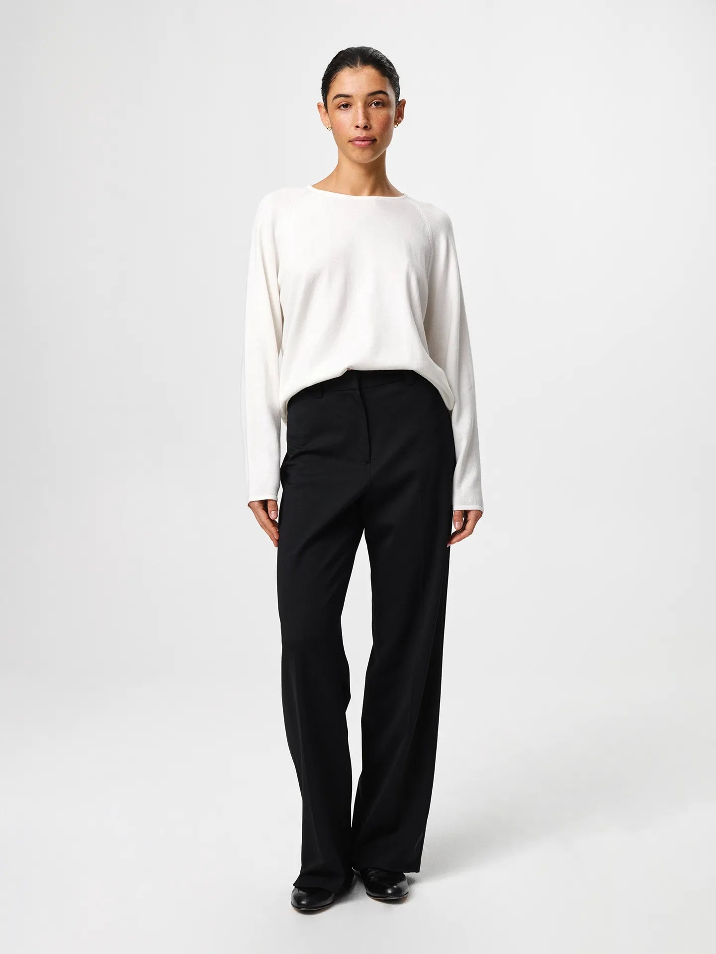 Julie Josephine Kate Roundneck Sweater Off White: product image of a soft, lightweight knit sweater in an off white shade, made from a wool and cotton blend that combines warmth with breathability, designed with a relaxed silhouette, long sleeves, subtle dropped shoulders, and a clean neckline, styled for easy everyday layering over a T shirt or worn on its own with tailored trousers or denim.