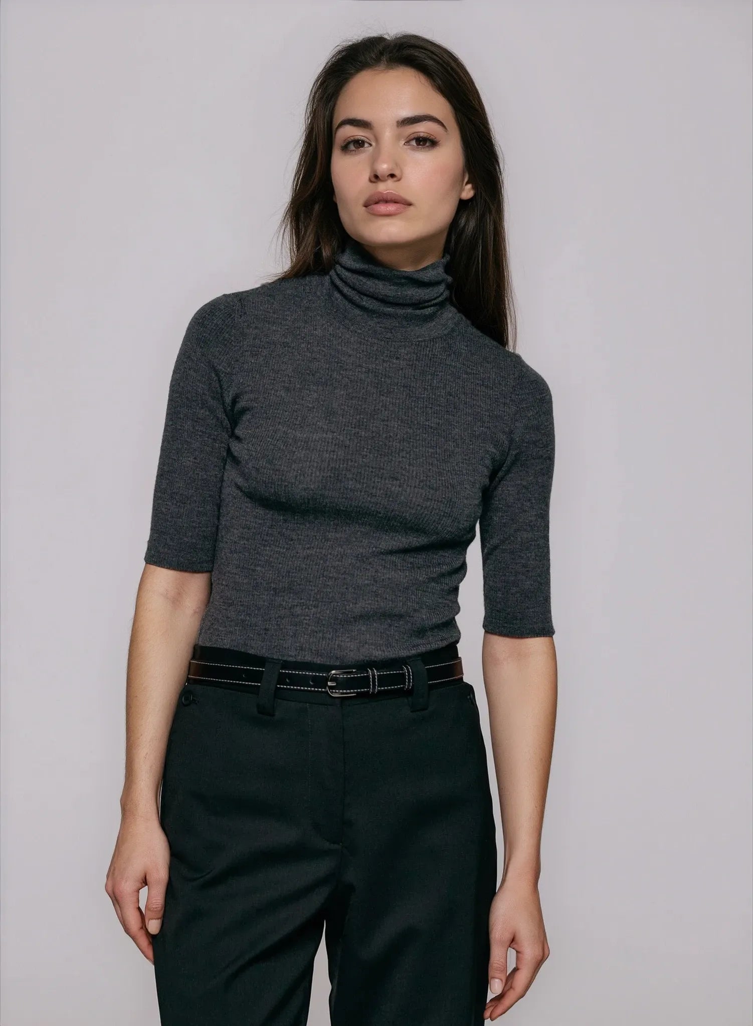 Model wearing the Kristin Top in grey from Julie Josephine — a fitted turtleneck in lightweight merino wool rib knit with short sleeves and a clean, modern silhouette.